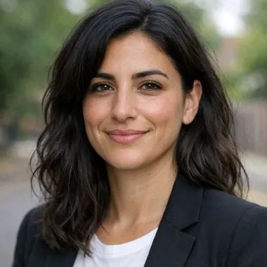 Early-30s woman, olive skin, wavy dark hair, relaxed expression, dark blazer